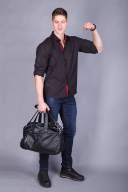 Stüdyo fotoğrafçılığı, büyük bir siyah çanta tutarak ellerinde siyah tişört ve kot giyen genç güçlü uzun boylu, yakışıklı adam
