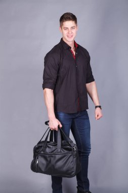 Stüdyo fotoğrafçılığı, büyük bir siyah çanta tutarak ellerinde siyah tişört ve kot giyen genç güçlü uzun boylu, yakışıklı adam