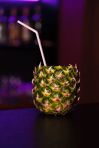 Cocktail in a pineapple at the bar on a dark background of night club — Stock Photo, Image