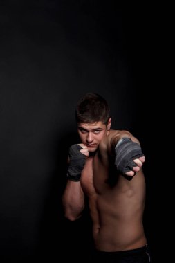 Siyah bir arka plan üzerinde boks kaslı atletik adam. Bir adam şort, çıplak bir gövde ile peremotanye bandajlar boks için eller.