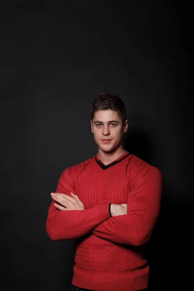 素敵な男性は、黒の背景の上に立って。赤いセーターに身を包んだ非常にハンサムな男. — ストック写真