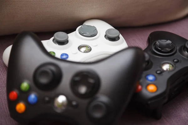 Gamepad berbaring di sofa. Putih dan dua hitam joypad . — Stok Foto