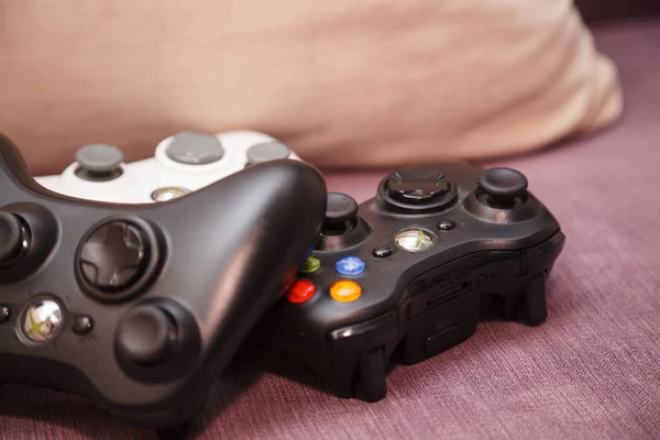 O Gamepad está no sofá. Branco e dois joypad preto . — Fotografia de Stock