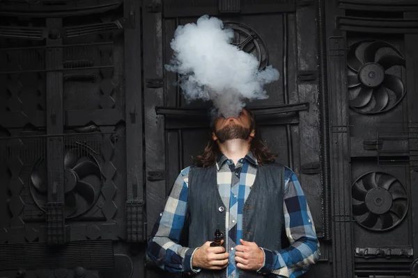 Sakal vaping siyah arka plan üzerine erkeklerle. Uzun saçlı genç adam elektronik sigara içiyor. 