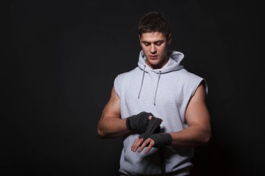 Atletik adam ellerini bandaj boks için bandaj. Giyinmiş bir adam gri bir hoodie.