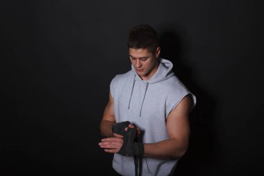 Atletik adam ellerini bandaj boks için bandaj. Giyinmiş bir adam gri bir hoodie.
