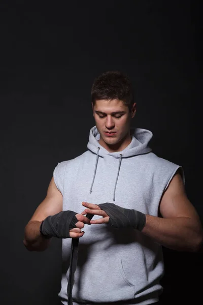 Un sportif se pansant les mains pour des bandages de boxe. Un homme habillé d'un sweat à capuche gris . — Photo