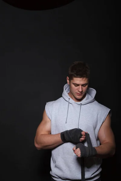 Un atleta che bendava le mani per delle bende da boxe. Un uomo vestito con una felpa grigia . — Foto Stock
