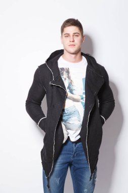 Beyaz arka plan üzerinde duran şık delikanlı. Adam elini onun cep hoodies