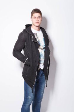 Beyaz arka plan üzerinde duran şık delikanlı. Adam elini onun cep hoodies