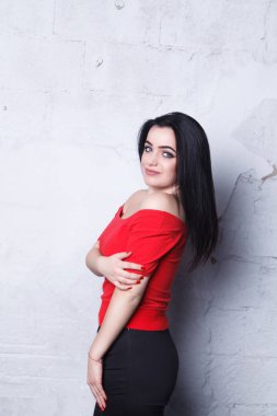 Şık kız siyah bir etek ve kırmızı bir tişört giymiş. Güzel kız beyaz tuğla arka plan duvar