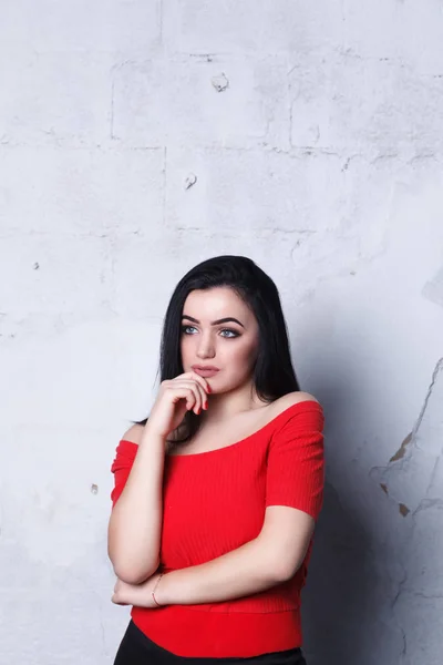 Elegante chica vestida con una falda negra y una camiseta roja. Hermosa chica en la pared de fondo de ladrillos blancos — Foto de Stock