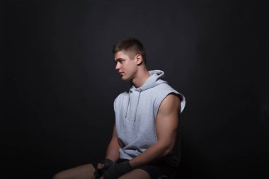 Genç kas boksör siyah bir arka plan bir sandalyede oturur