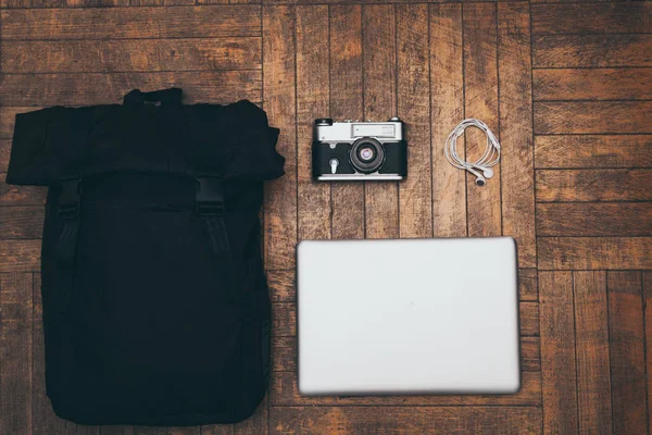 Cámara de película, bolso, auriculares y un portátil sobre un fondo de madera . —  Fotos de Stock