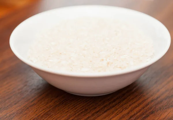 Assiette blanche avec riz sur fond en bois — Photo