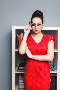 Gözlüklü şirin genç iş kadını portresi. Kırmızı elbiseli bir kadın