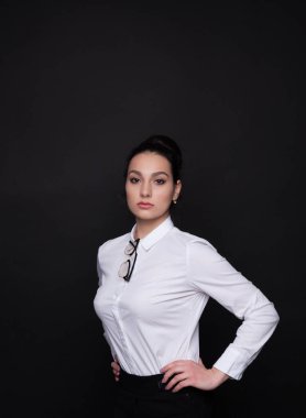 Genç başarılı iş kadını. Kız beyaz bir bluz siyah bir arka plan üzerinde