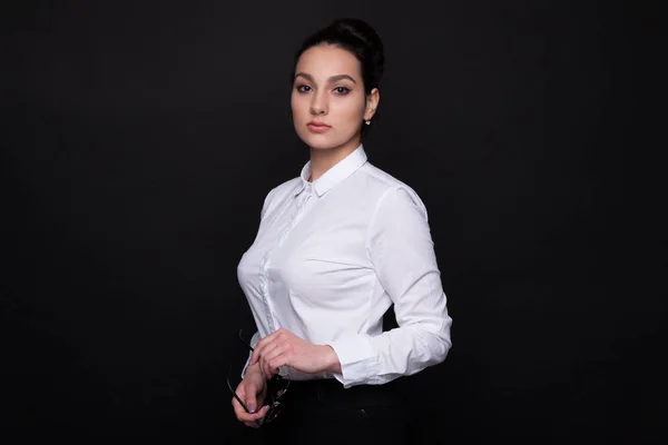 Joven mujer de negocios exitosa. Chica sobre un fondo negro en una blusa blanca — Foto de Stock