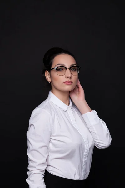Joven mujer de negocios exitosa en gafas negras. Chica sobre un fondo negro en una blusa blanca — Foto de Stock