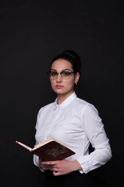 Mujer de negocios con un cuaderno en la mano sobre un fondo negro — Foto de Stock