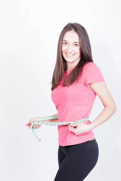 Спортивна струнка жінка вимірює талію за мірною стрічкою після дієти на білому тлі — стокове фото