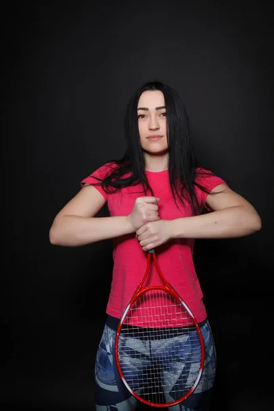 一个网球拍在黑色背景上的年轻女子 — 图库照片
