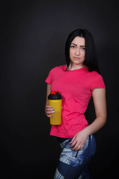 Sport woman in pink shirt holding a shaker — Stock Photo, Image
