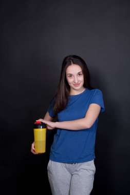 Genç kadın protein sallamak şişe siyah arka plan üzerine