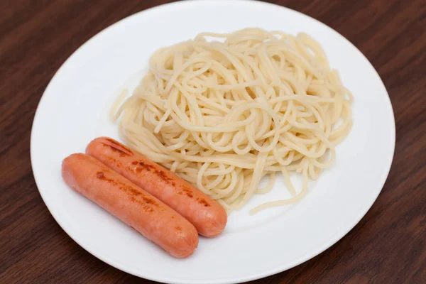 Spaghetti à la saucisse sur une assiette blanche — Photo