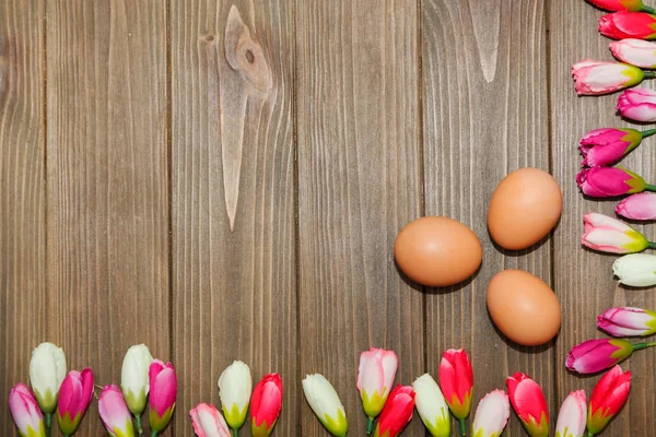 Яйца и тюльпаны на деревянном фоне — стоковое фото