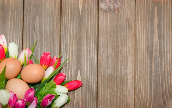 Тюльпаны и яйца на деревянном фоне — стоковое фото