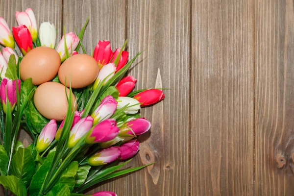 Тюльпаны и яйца на деревянном фоне — стоковое фото