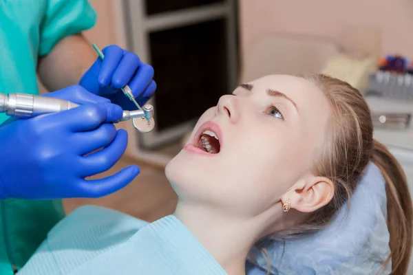 Dentista está tratando dentes para uma mulher — Fotografia de Stock