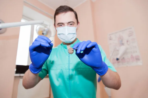 Retrato de um dentista masculino com ferramentas nas mãos — Fotografia de Stock