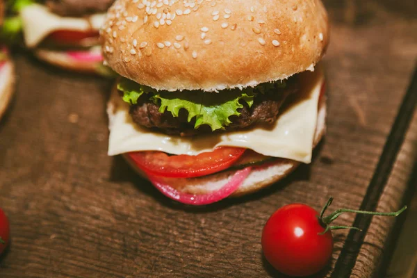Burger und kleine Tomaten an der Tafel — Stockfoto
