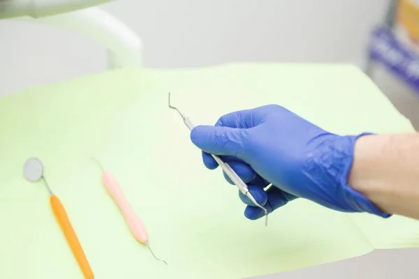 A mão do dentista em uma luva azul leva uma ferramenta — Fotografia de Stock