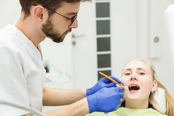 Młody mężczyzna dentysta jest leczenie zębów kobiety — Zdjęcie stockowe