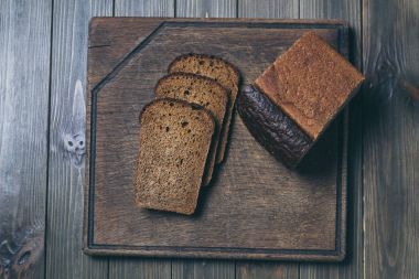 bir koyu ahşap tahta üzerinde yalan taze ekmek dilimlenmiş