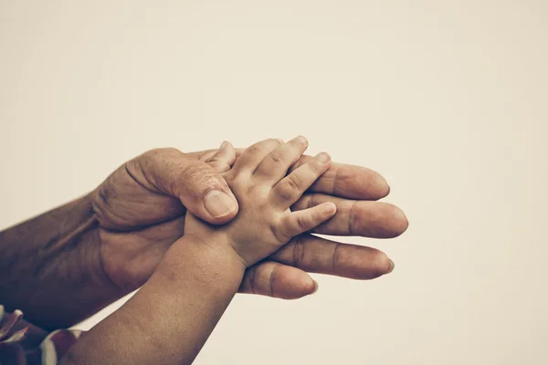 Gammal kvinnlig hand håller ung baby hand — Stockfoto