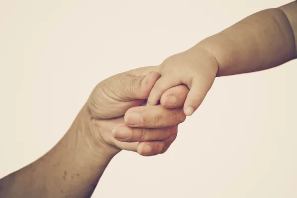 Gammal kvinnlig hand håller ung baby hand — Stockfoto