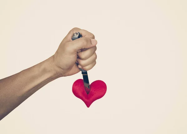 Hand with a knife stabbing into a red heart — Stock Photo, Image
