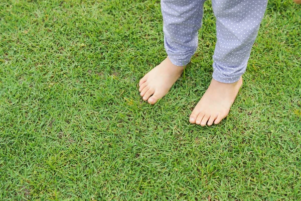 Kid fötter står på grönt gräs — Stockfoto