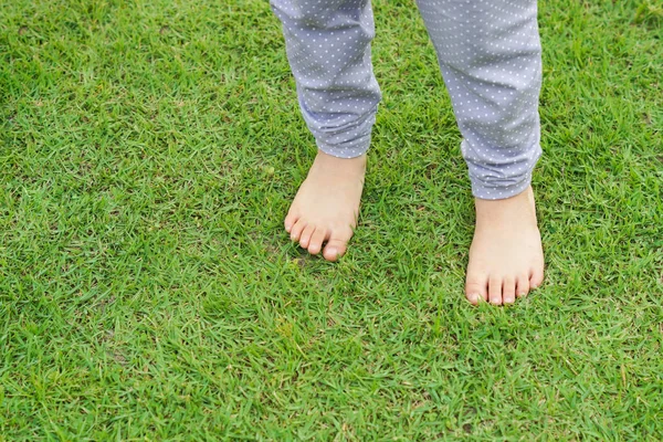 Kid fötter står på grönt gräs — Stockfoto