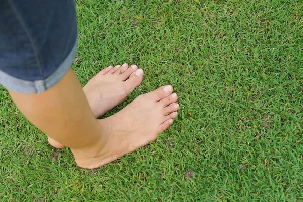 Kvinnliga fötter står på grönt gräs — Stockfoto