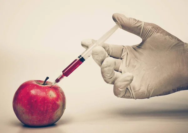 Mano inyectando químicos a la manzana — Foto de Stock