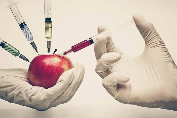 Hände injizieren Chemikalie in den Apfel — Stockfoto