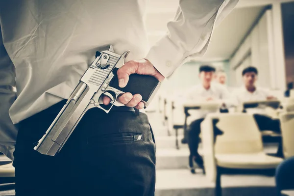 Een docent met een pistool in zijn hand in een collegezaal — Stockfoto