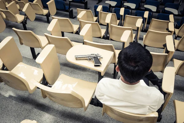 Een man met een pistool in een collegezaal — Stockfoto