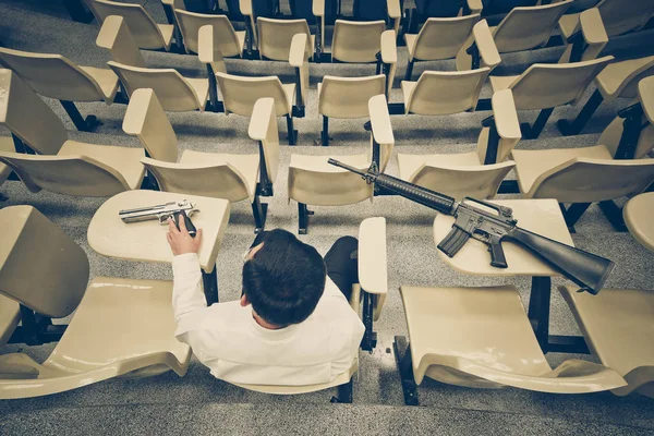Een man met een pistool in een collegezaal — Stockfoto