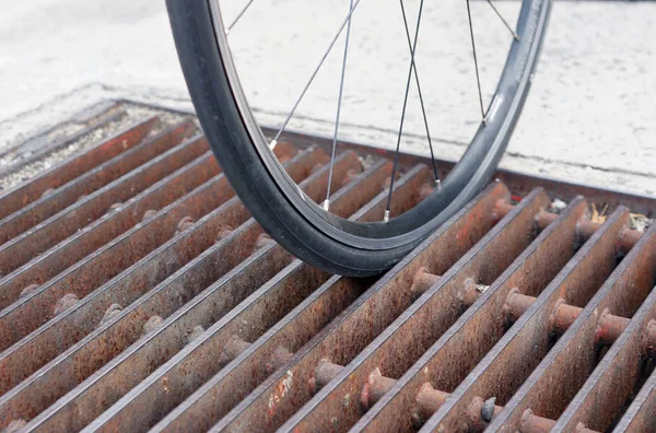 Bicycle wheel falls down and stuck in the drain lid — Stock Photo, Image